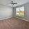 Empty bedroom at Camber Ranch with ceiling fans, neutral walls, carpeted floor, and a large window allowing natural light