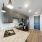 Modern kitchen and bar area featuring sleek cabinetry, a spacious countertop, contemporary appliances, and stylish barstools